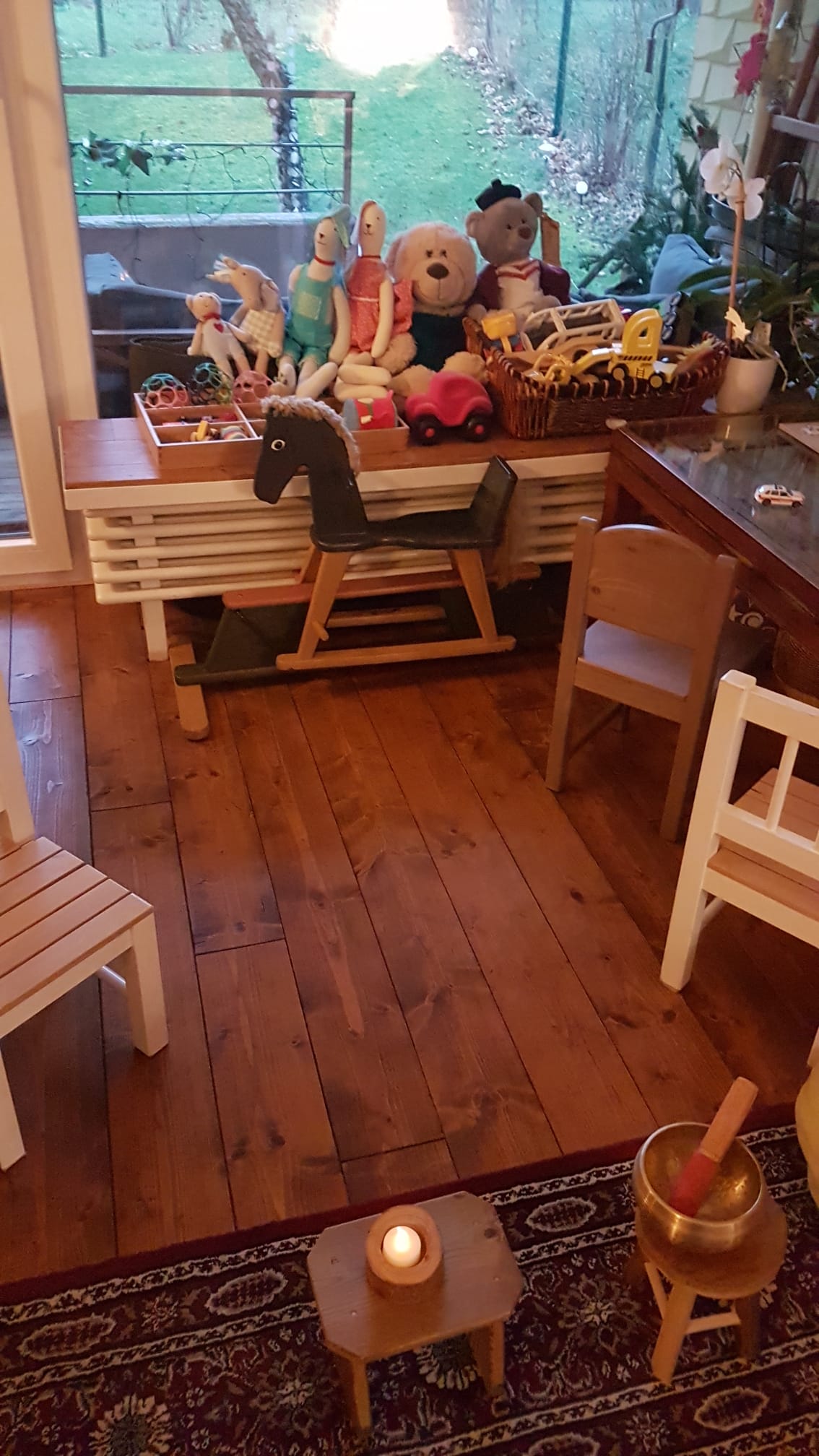 Gemütliches Spielzimmer mit Holzboden, Schaukelpferd, Plüschtieren und Kindermöbeln